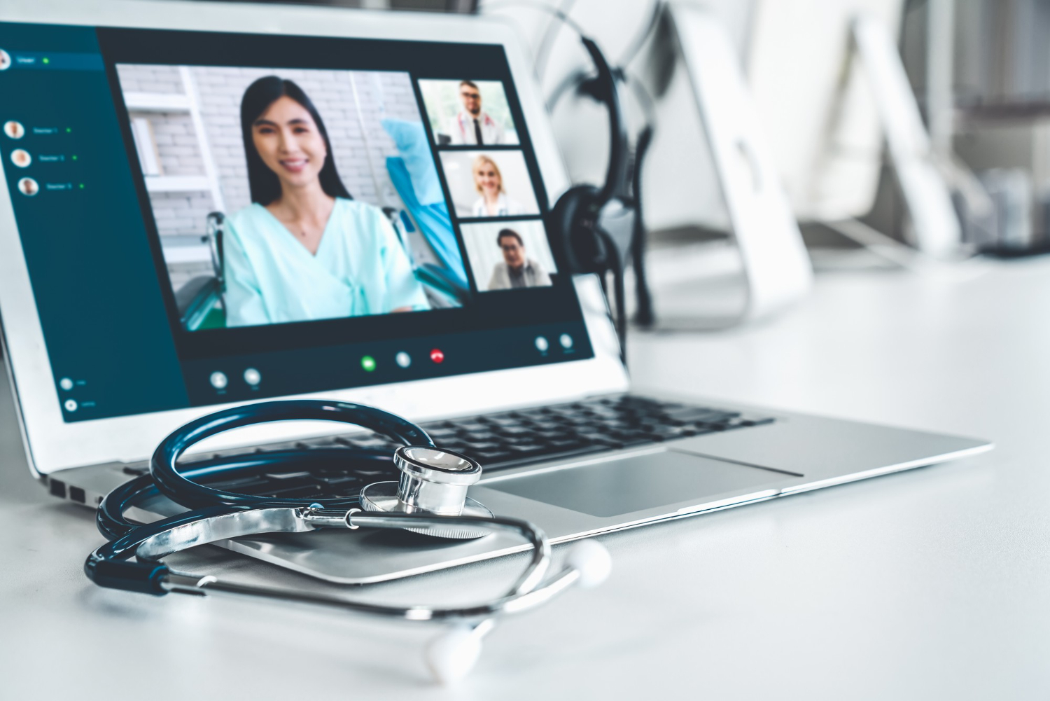 Laptop showing a virtual medical consultation, with a stethoscope resting beside it on the desk.