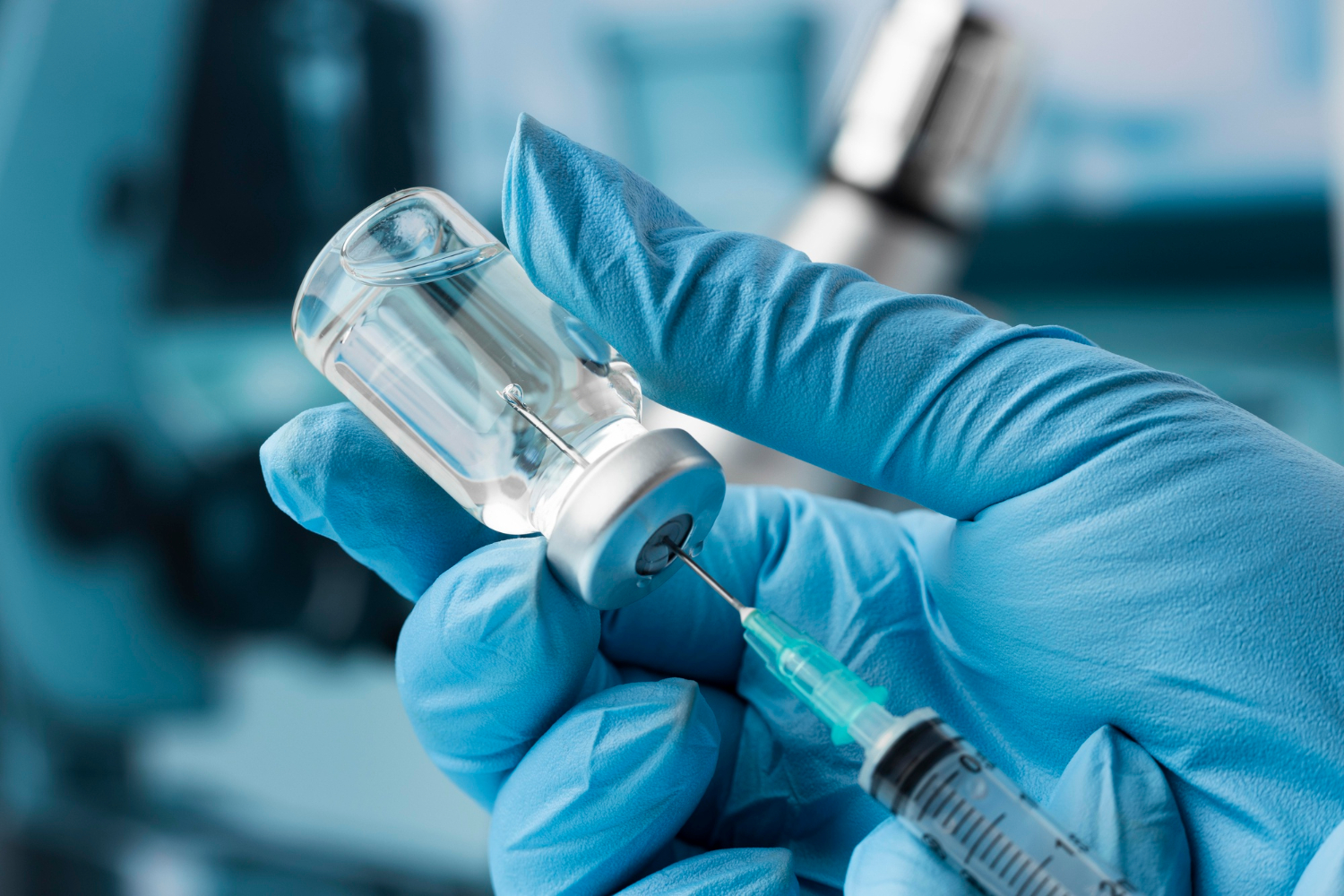 Gloved hands drawing liquid from a vial with a syringe in a laboratory setting.